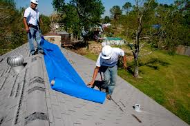 YICN emergency tarping team installing blue tarp on residential roof for storm damage protection